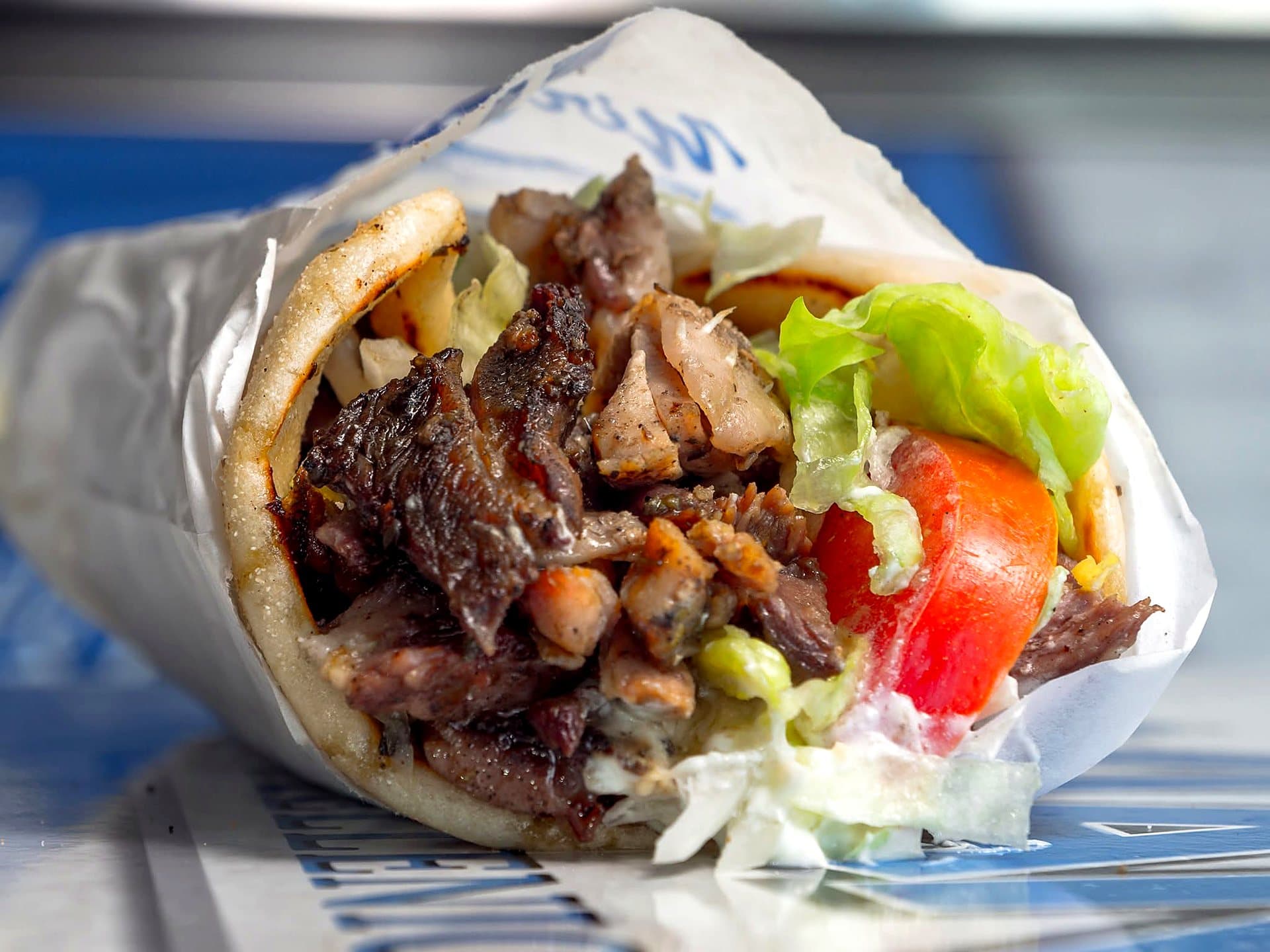 A charcoal yiros with tomato and lettuce, wrapped in Yianni's paper